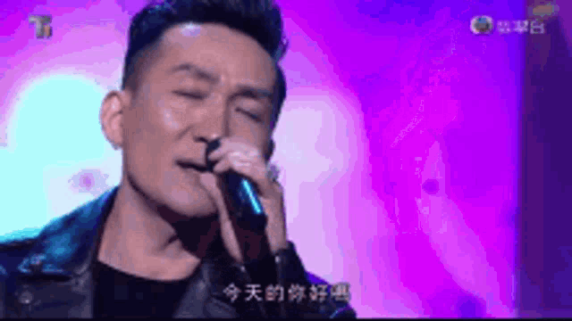 a man is singing into a microphone with a purple background