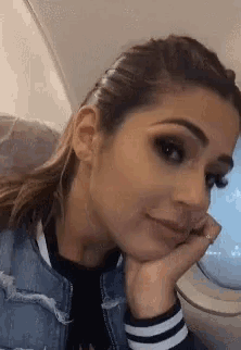 a woman is sitting on a plane with her hand on her face .
