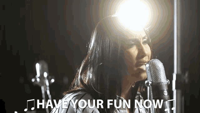 a woman singing into a microphone with the words have your fun now