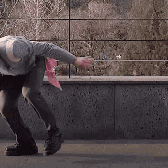 a person wearing a gray sweatshirt and black pants is standing on a sidewalk