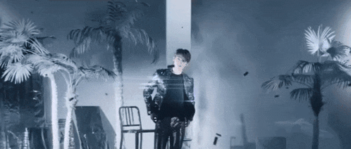 a man is standing next to a chair in a room with palm trees in the background .