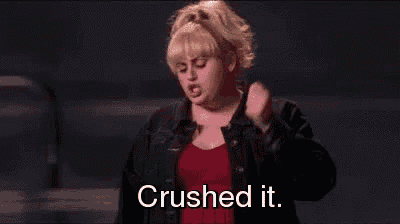 a woman in a red dress and a denim jacket is standing in front of a crowd and says `` crushed it '' .