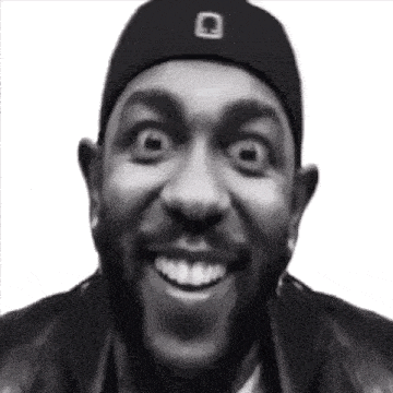 a black and white photo of a man wearing a hat and a jacket making a funny face .