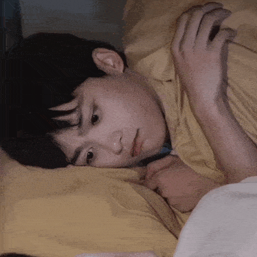 a young boy is laying on a bed with a yellow blanket