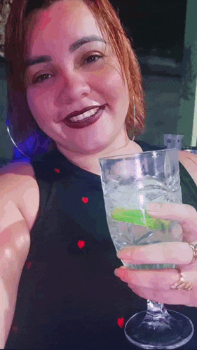 a woman is taking a selfie while holding a glass of water .