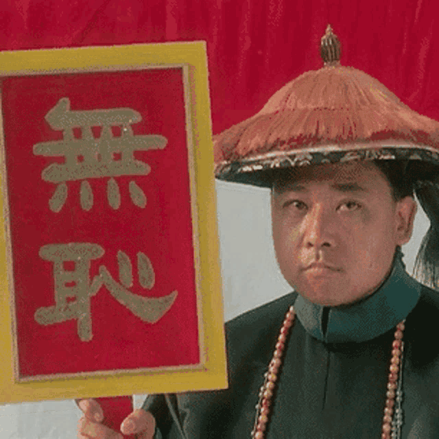 a man wearing a hat is holding a sign with chinese writing