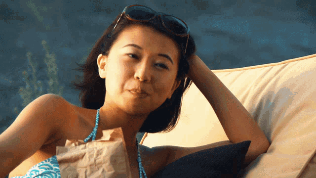 a woman in a bikini is sitting on a couch holding a bag of food