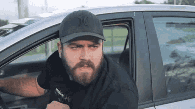 a man with a beard is sitting in a hurley hat