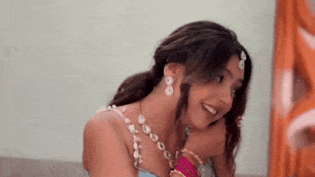 a woman is sitting on a couch wearing a blue dress and earrings .