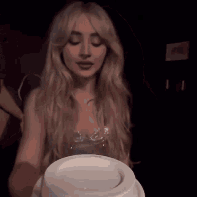 a woman with long blonde hair is holding a white cup