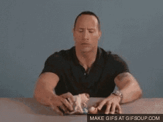 a man in a black shirt is sitting at a table with his hands on a piece of paper .