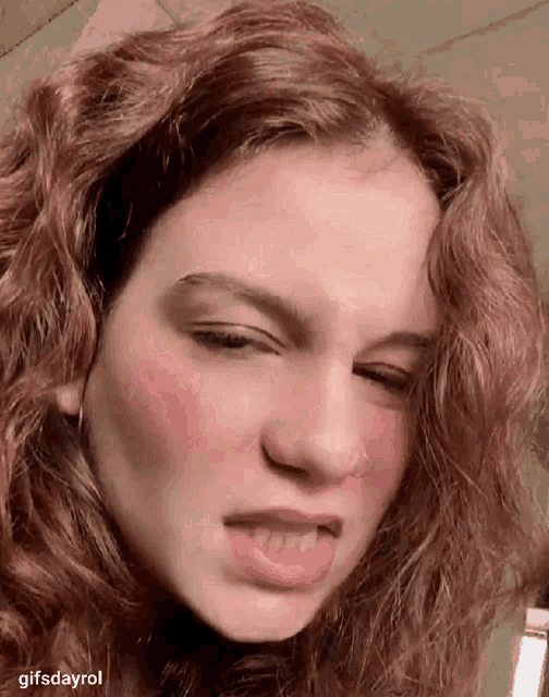 a close up of a woman 's face with red hair and a nose ring .