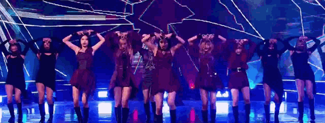 a group of women are dancing on a stage in front of a purple background