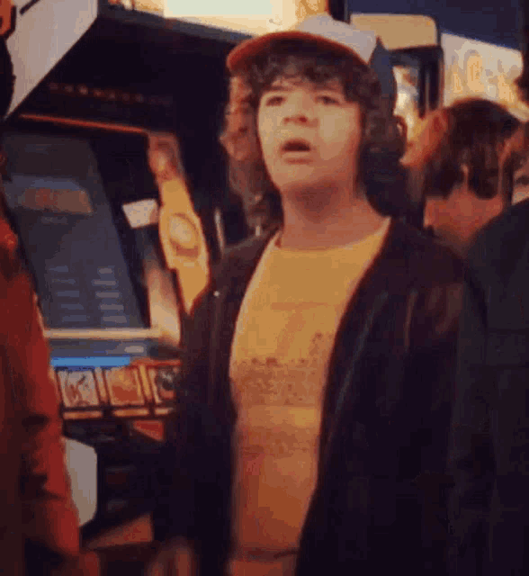 a man wearing a hat is standing in front of an arcade