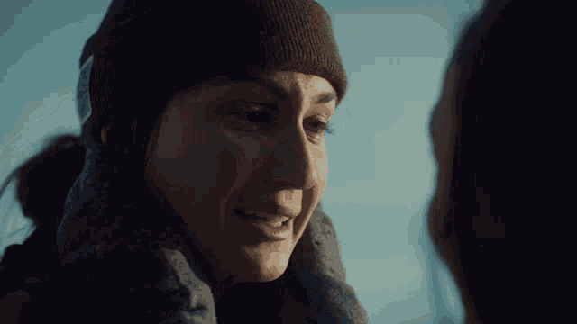 a woman in a beanie looks at another woman