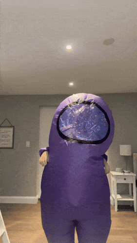a person in a purple among us costume is standing in a living room