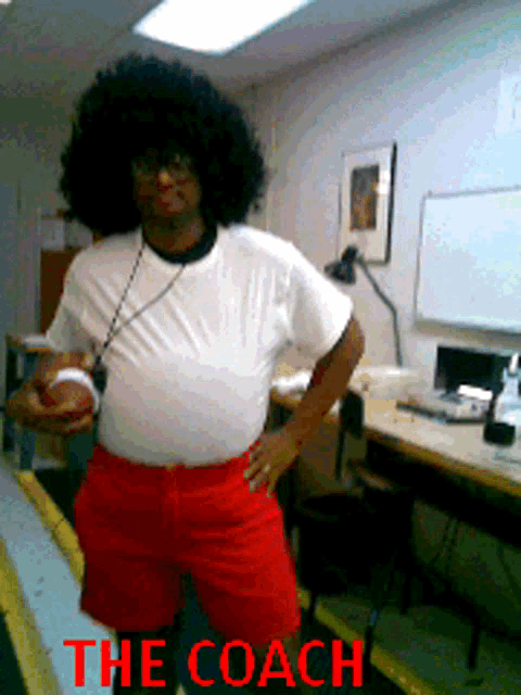 a man in a white shirt and red shorts is standing in a room with the coach written on the bottom