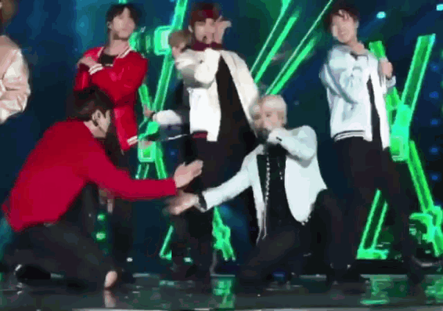 a group of men are dancing on a stage in front of a green screen .