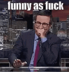 a man in a suit and tie is laughing while sitting at a table .