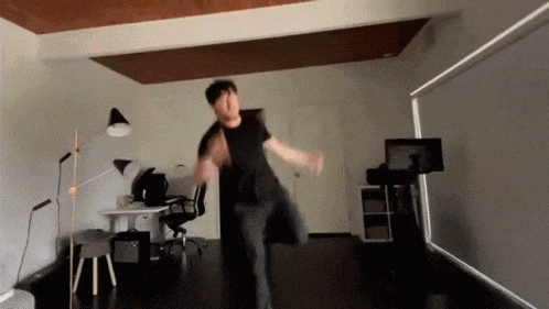 a man in a black shirt is jumping in the air in a room