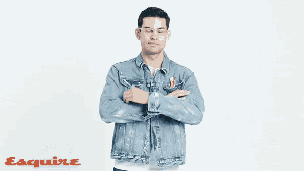 a man in a blue denim jacket is standing with his arms crossed in front of an esquire ad