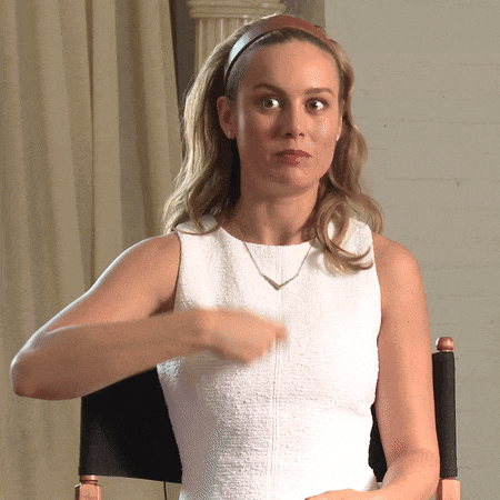a woman in a white dress is sitting in a chair with her hand on her chest