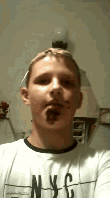 a young man wearing a nyc t-shirt is taking a picture of himself