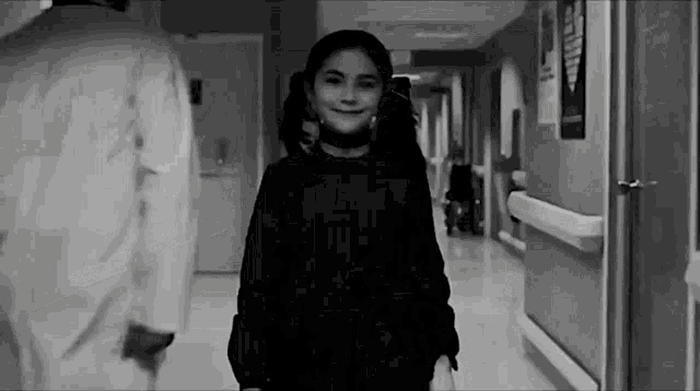 a black and white photo of a young girl in a hospital hallway
