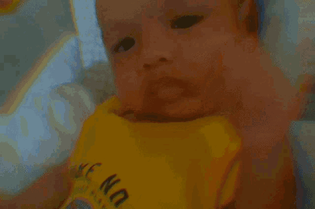 a baby is wearing a yellow shirt that says " wake no "