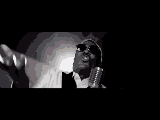 a black and white photo of a man singing into a microphone .