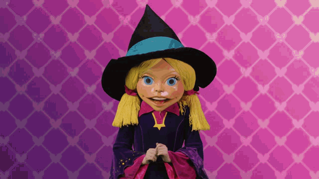 a doll in a witch costume stands in front of a purple background