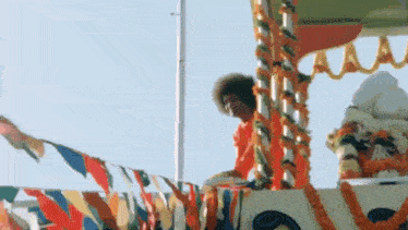 a man is sitting on top of a float with flags and garlands on it .