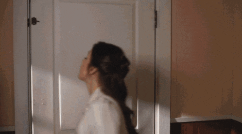 a woman is standing in front of a door looking up
