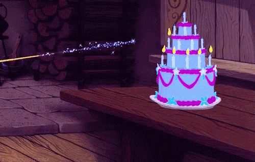 a blue and purple birthday cake with candles on a table
