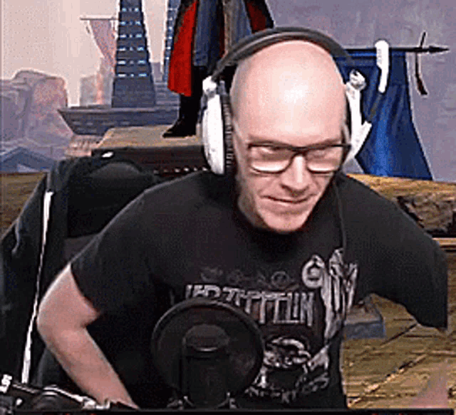 a bald man wearing headphones and a led zeppelin shirt is sitting in front of a microphone .