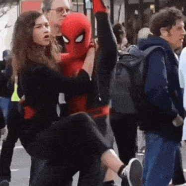 a man in a spiderman costume is holding a woman in his arms .
