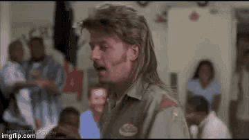 a man with a mullet and mustache is standing in front of a crowd of people .