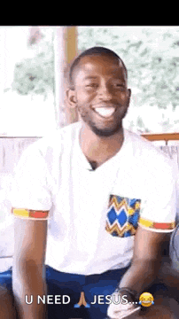 a man in a white shirt and blue shorts is smiling while sitting on a chair .