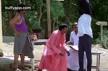 a man in a pink robe is kneeling down next to another man in a white shirt .