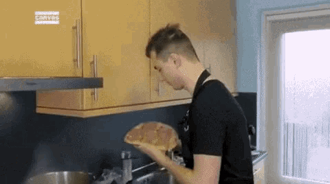 a man is cooking in a kitchen and holding a piece of bread .
