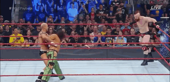 two wrestlers are fighting in a wrestling ring with a crowd watching .