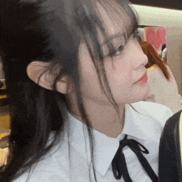 a close up of a girl 's face with a white shirt and black tie
