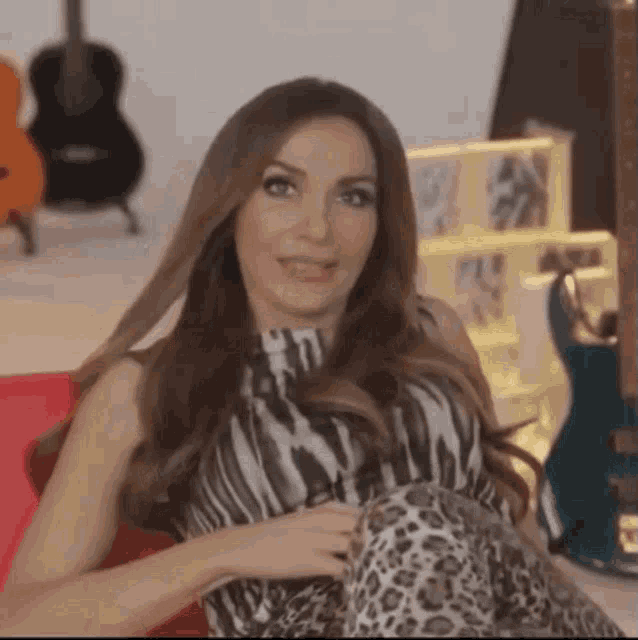 a woman in a zebra print dress is sitting on a red couch .