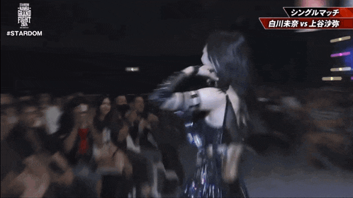 a woman stands in front of a crowd with the words #stardom on the bottom left