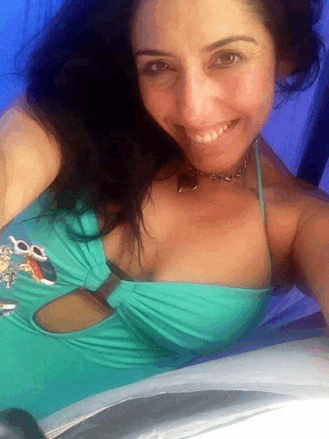 a woman in a blue swimsuit is smiling and wearing a necklace