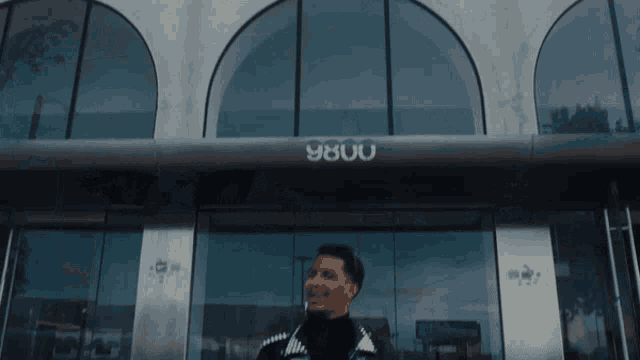a man stands in front of a building with the number 8800