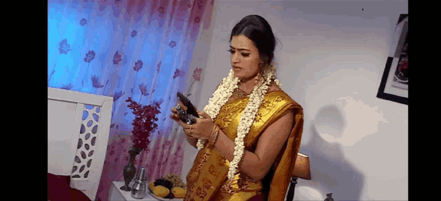 a woman in a yellow saree is looking at herself in the mirror .