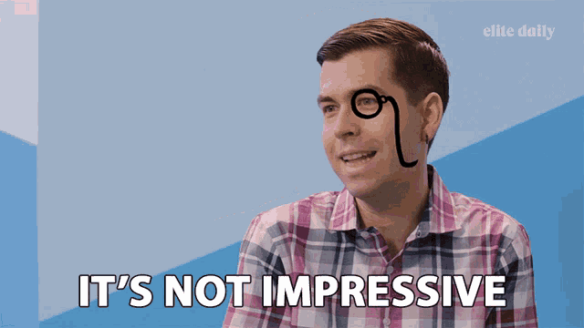 a man in a plaid shirt says it 's not impressive in front of a blue wall