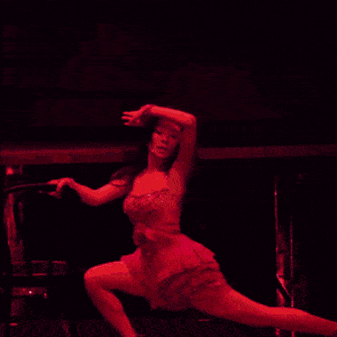 a woman in a red dress is dancing on stage .