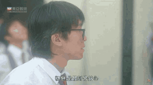 a man wearing glasses and a white shirt with chinese writing on the bottom